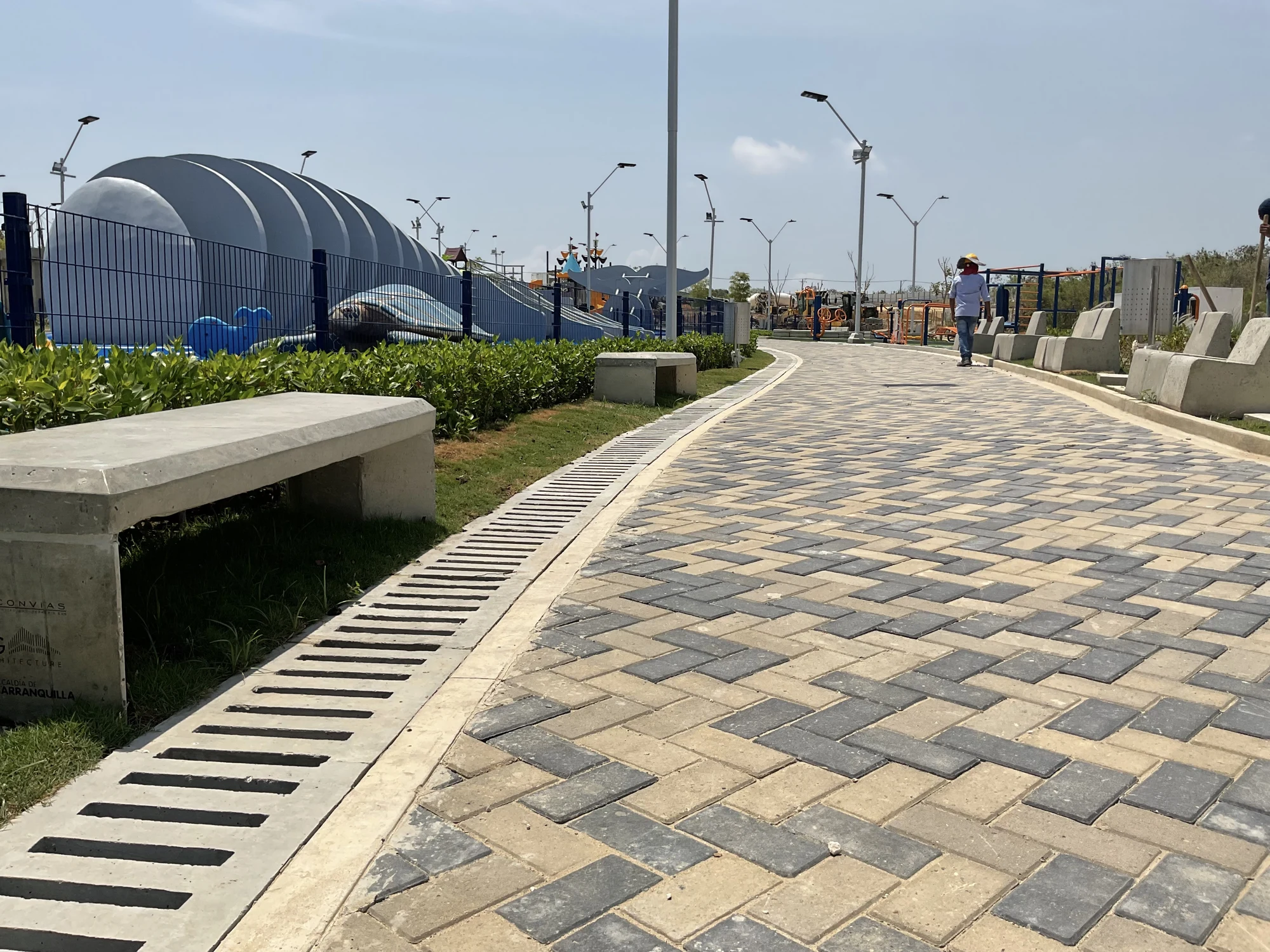 Paseo peatonal en adoquines curvos, bancas de concreto y drenajes en Quilla Park Barranquilla por Jardines & Rocas