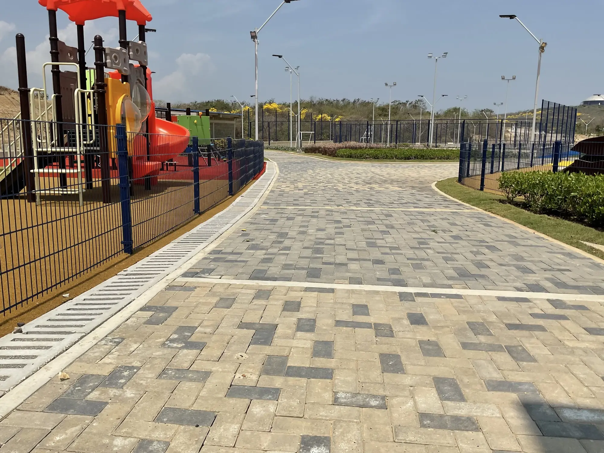 Paseo perimetral y canales de drenaje en concreto frente a zona de juegos infantiles