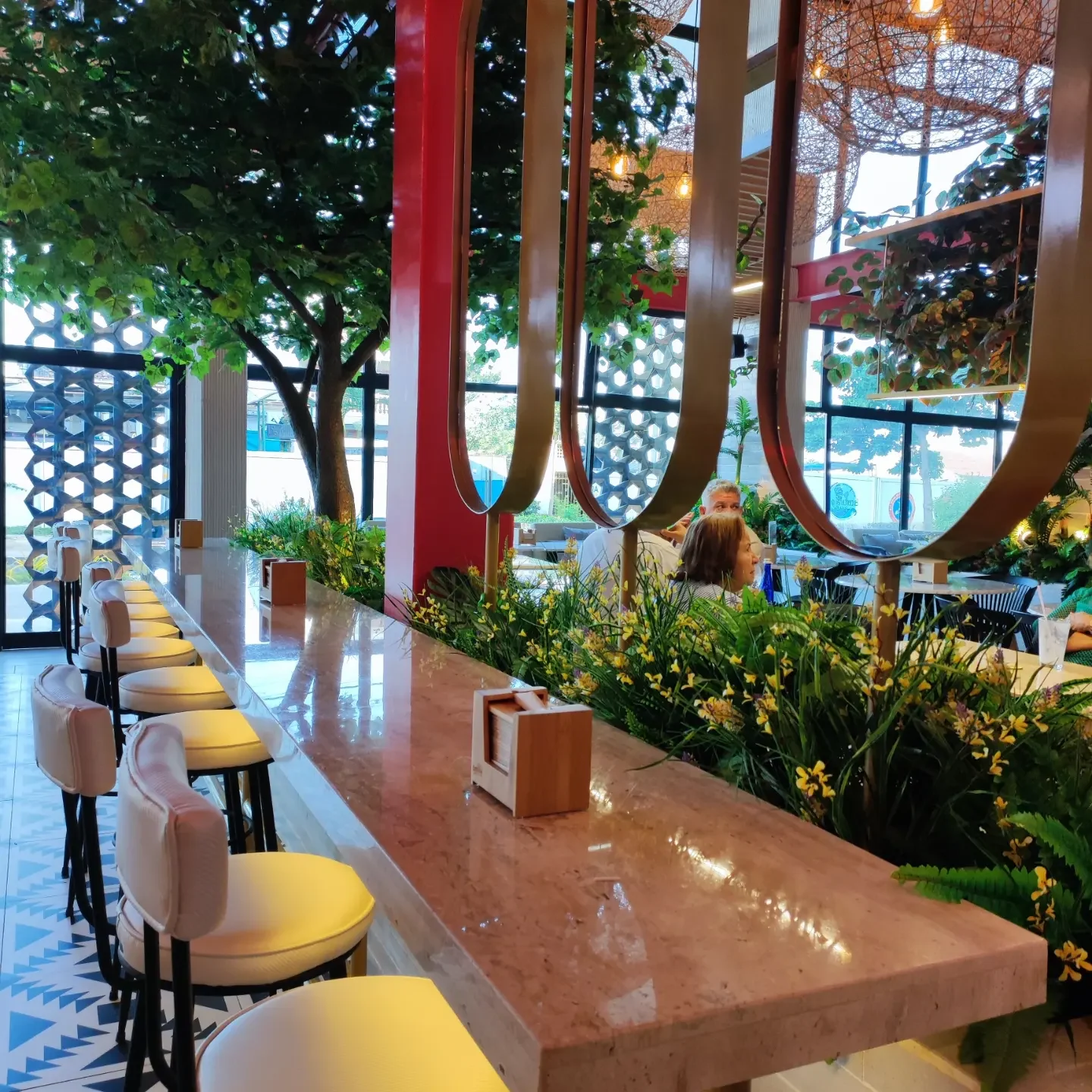 Perspectiva de la barra en mármol, aros dorados y jardinera en flor