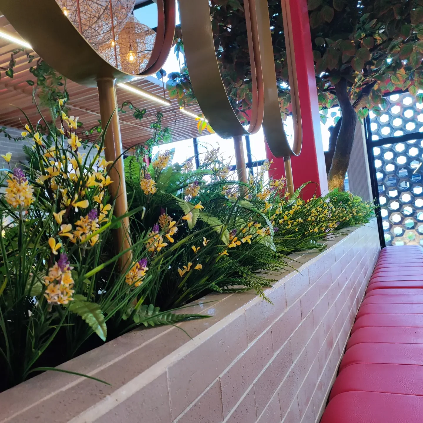 Jardinera longitudinal a lo largo de la banqueta roja y pérgola superior
