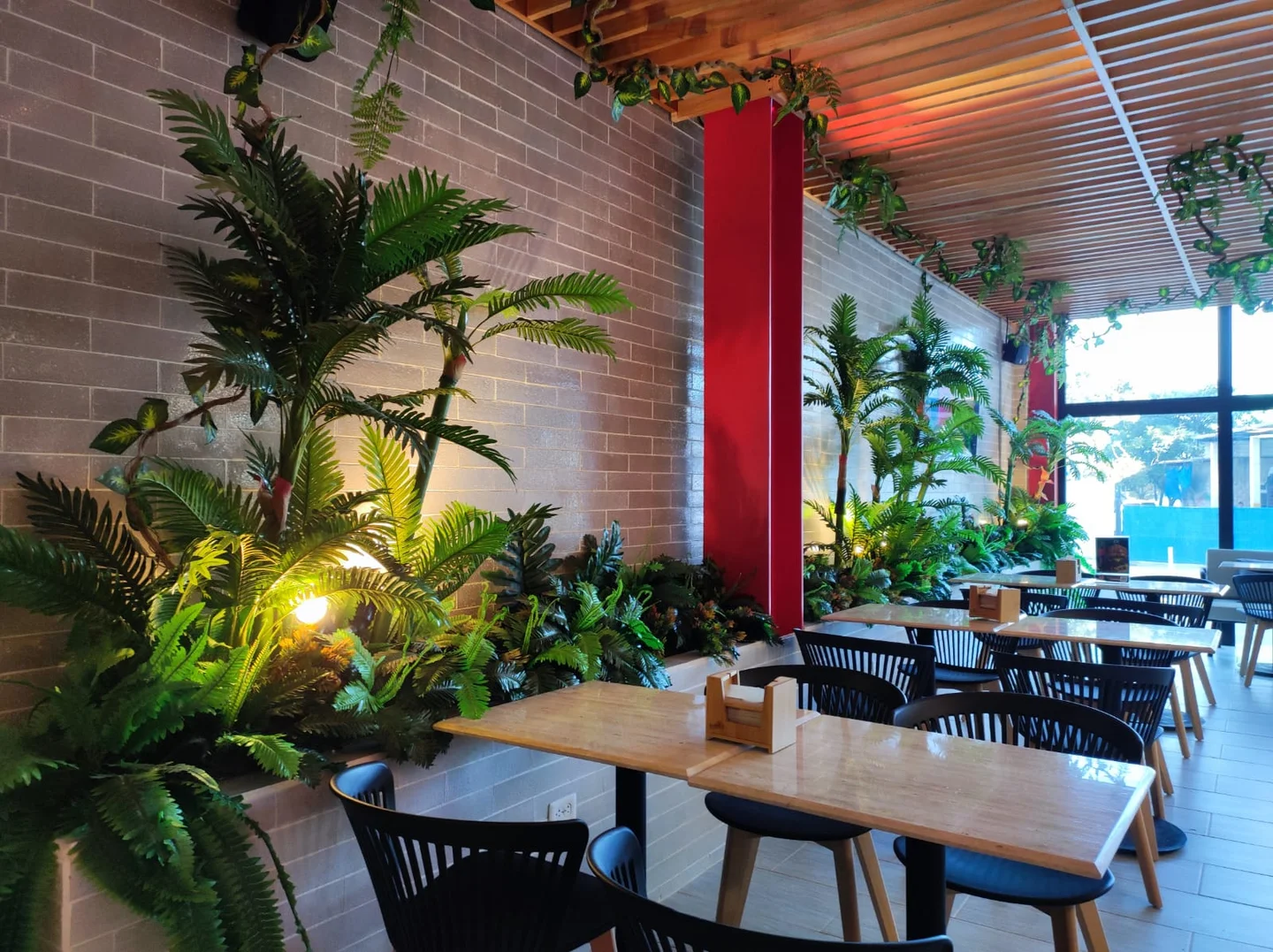 Jardineras perimetrales sobre muro, vegetación colgante en cielo raso e iluminación cálida