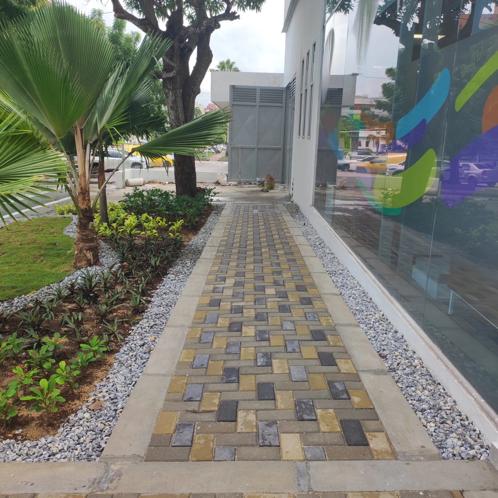 Sendero peatonal terminado en adoquines con jardineras y vegetación tropical en Bancolombia
