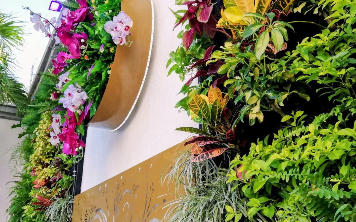 Jardín vertical arquitectónico con celosía calada retroiluminada, orquídeas y vegetación viva por Jardines & Rocas